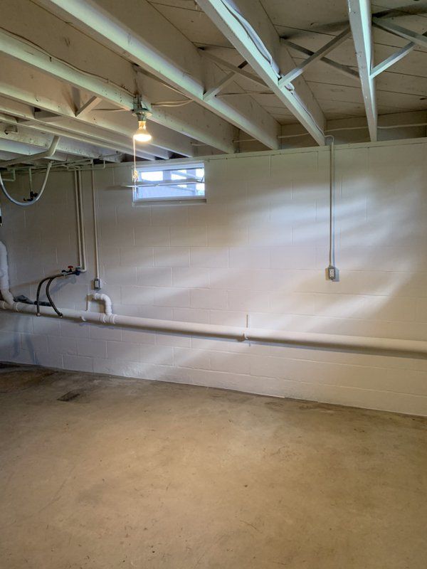 A basement with a lot of pipes and a window.