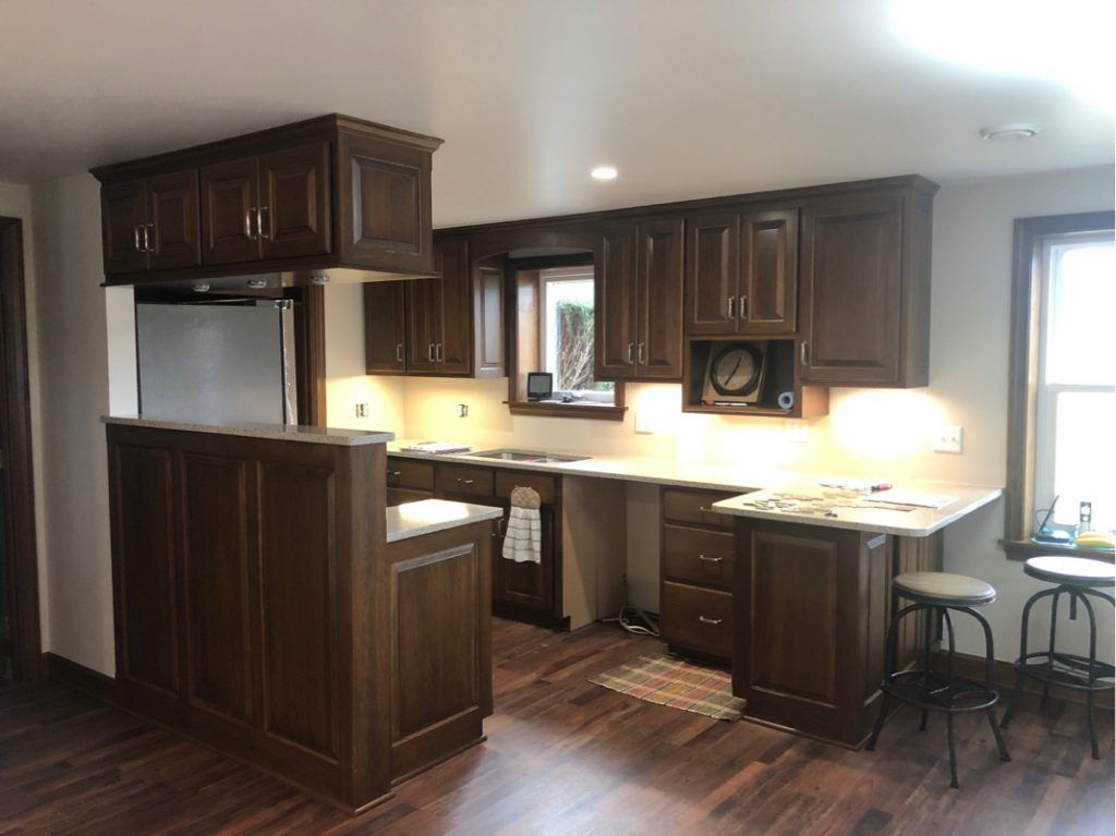 A kitchen with wooden cabinets and stools and a window.