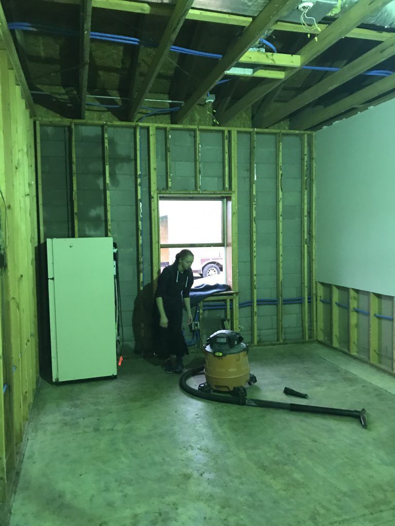 A person is standing in a room with an industrial vacuum. 