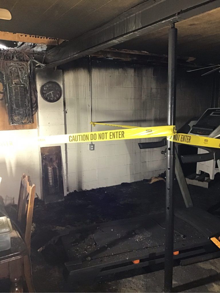 Corner of the basement blocked off by tape, the ceiling and ground is completely burnt.