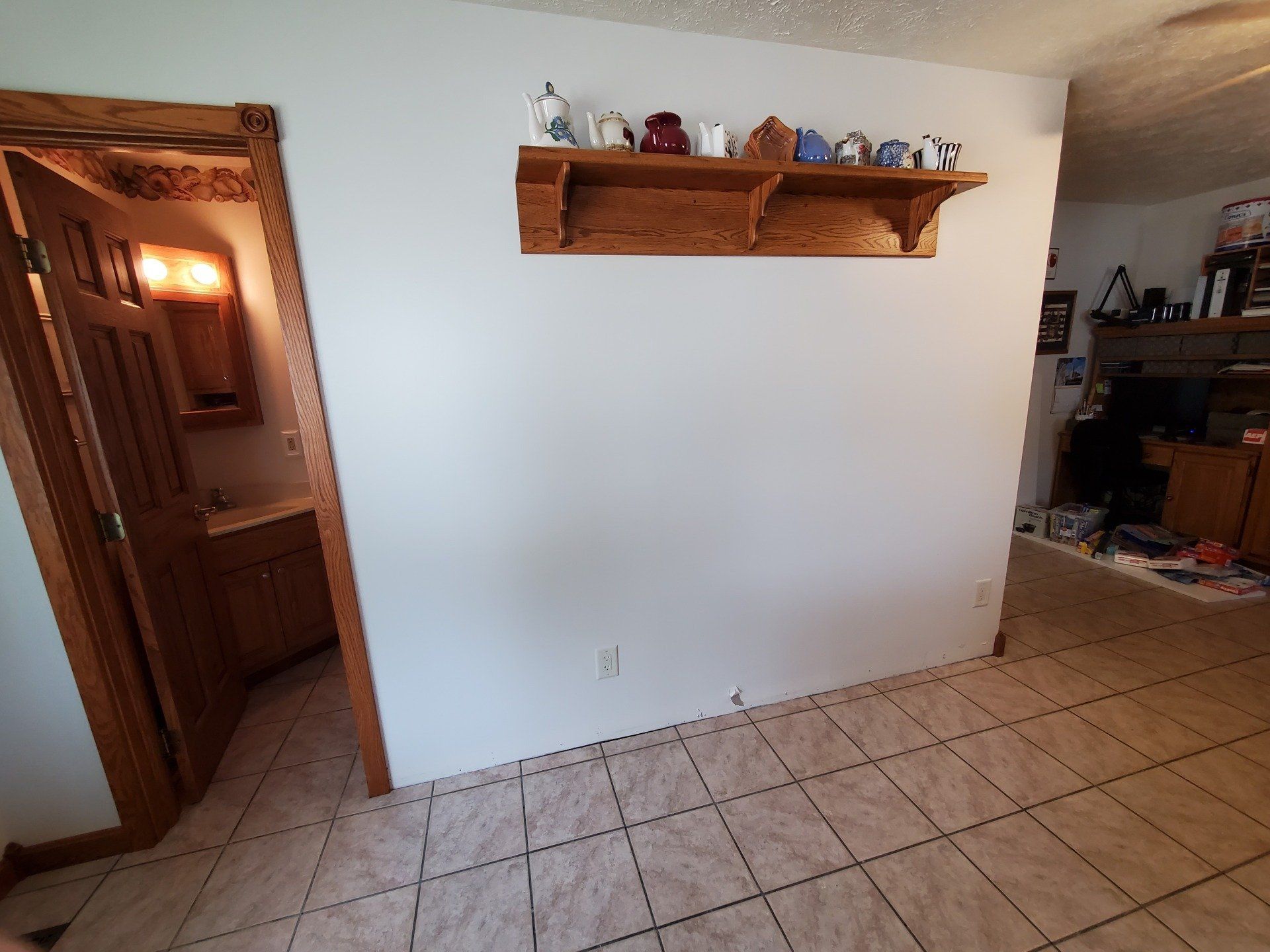 A white wall with a wooden shelf on it. 