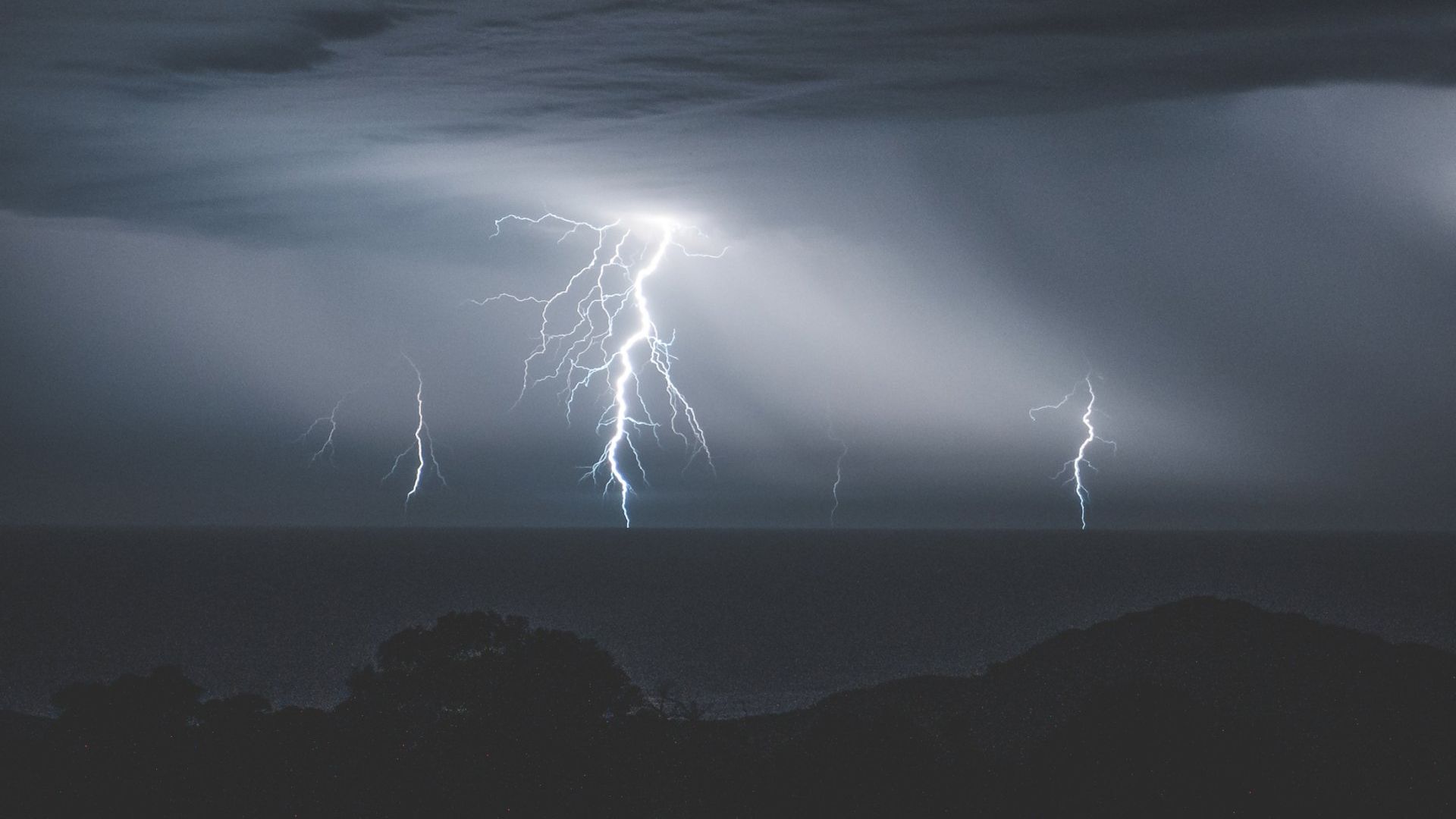 There is a lot of lightning in the sky over the ocean.