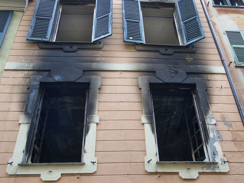 A building with windows and shutters which have been damaged by fire.