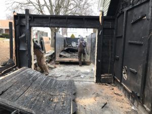 Two men working on damaged structure. 