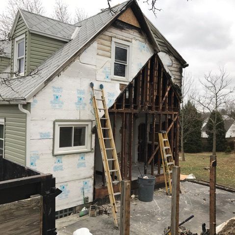 A house that is being remodeled with two ladders on the side.