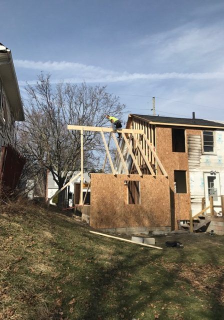 A man is standing on top of a house under construction.
