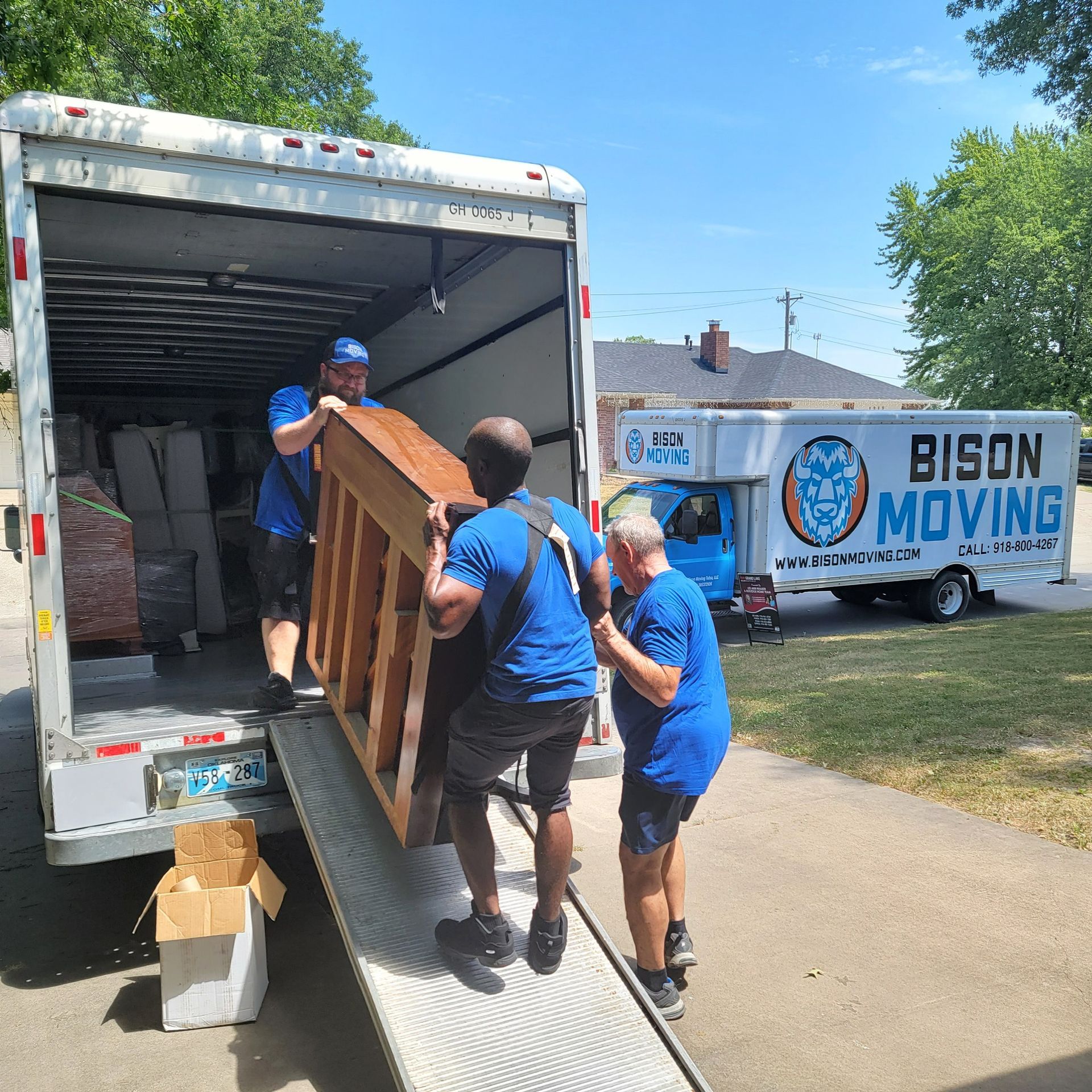 A group of men are loading a piece of furniture into a bison moving truck - Tulsa, OK - Bison Moving