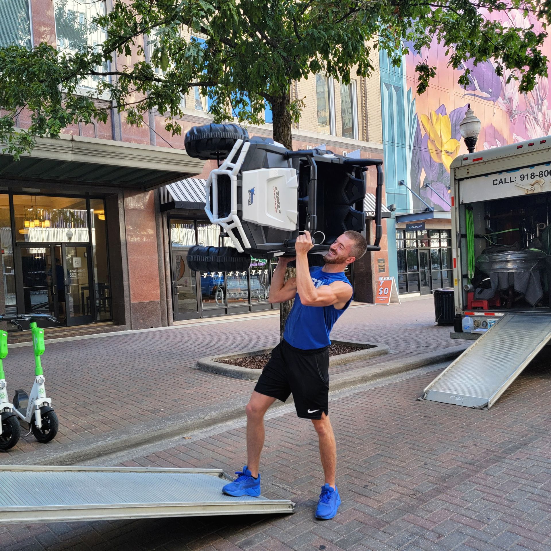 A man in a blue shirt is carrying a chair on his shoulders - Tulsa, OK - Bison Moving