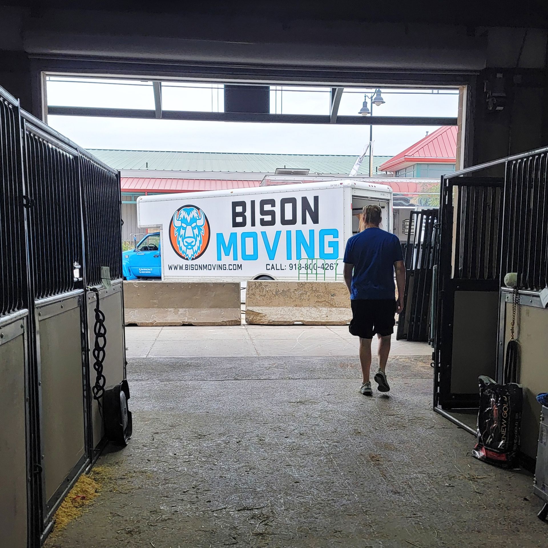 A man is walking through a barn with a sign that says bison moving - Tulsa, OK - Bison Moving