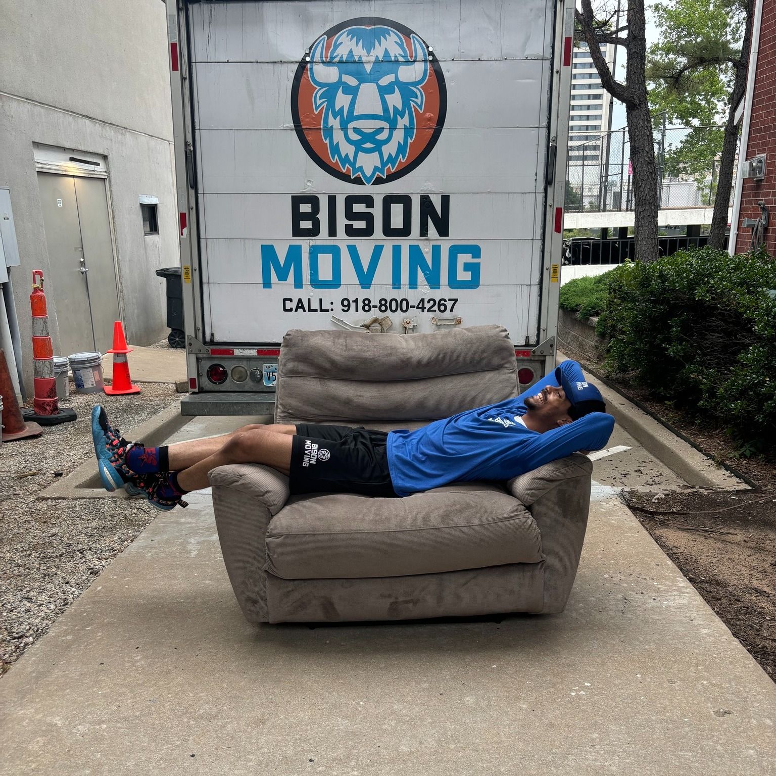 A man is laying on a chair in front of a bison moving truck - Tulsa, OK - Bison Moving