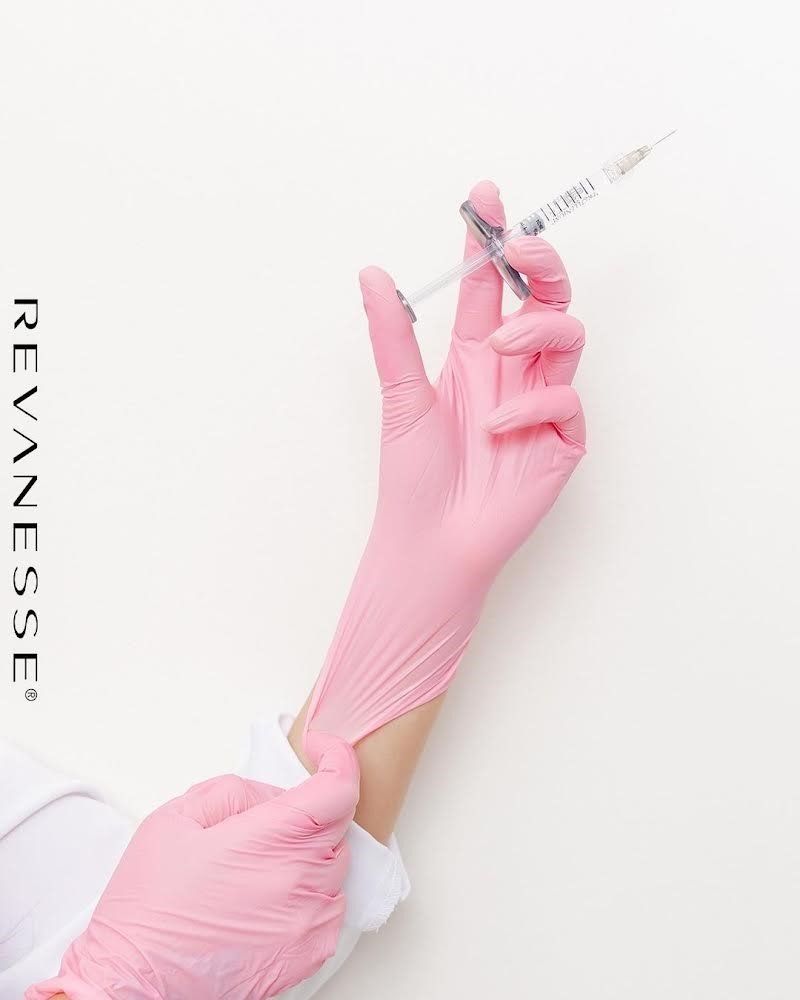A person is putting on gloves and holding a syringe. A person is putting on gloves and holding a syringe.