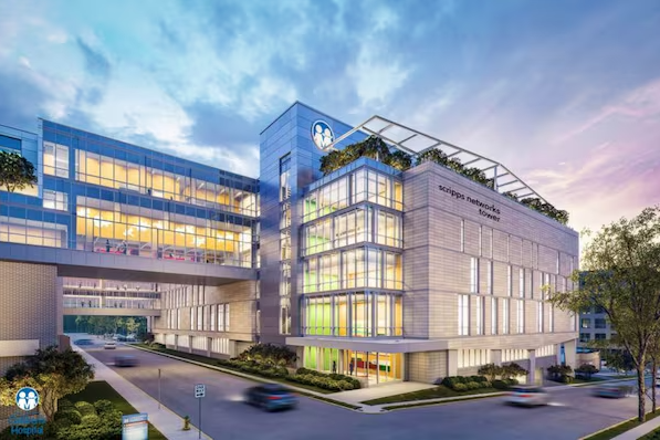 Modern glass office building at dusk with lit windows, skybridge, and landscaped entrance