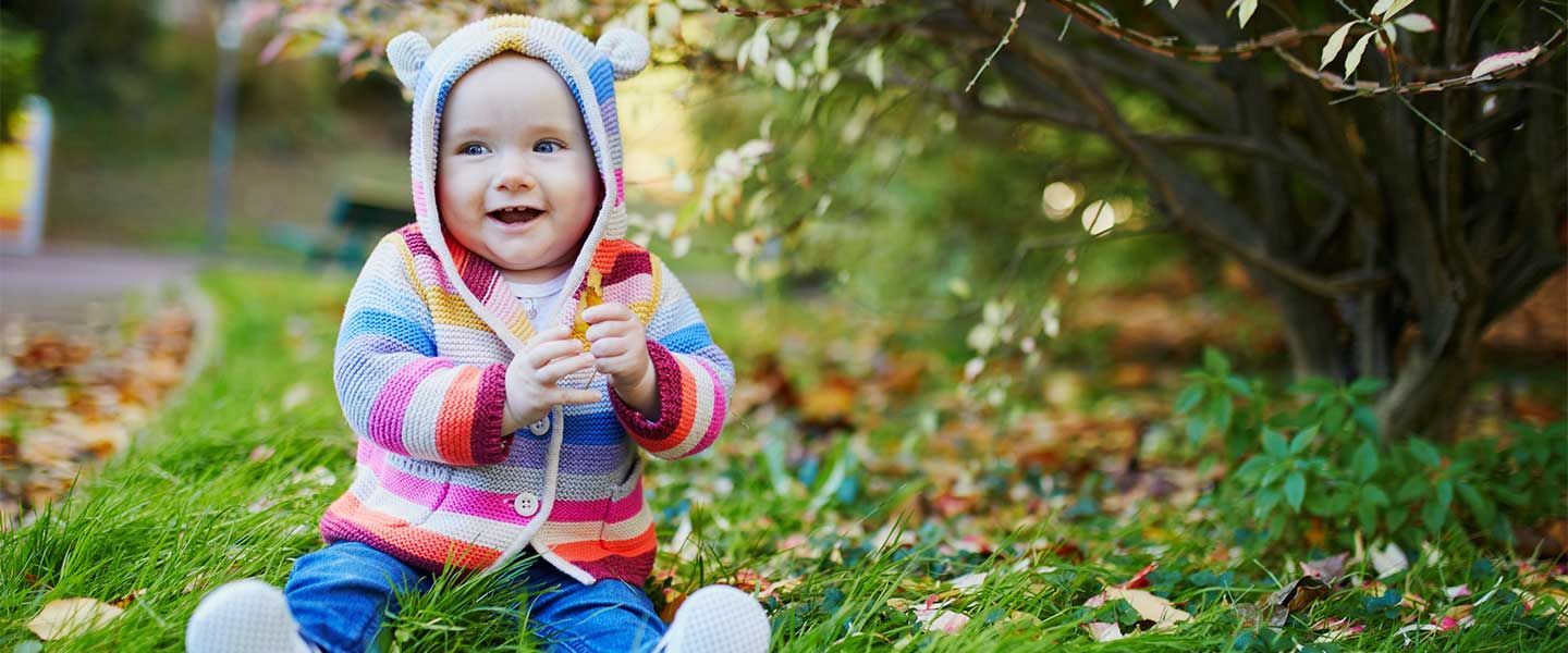 Toddler sitting in the grass in a colorful outfit