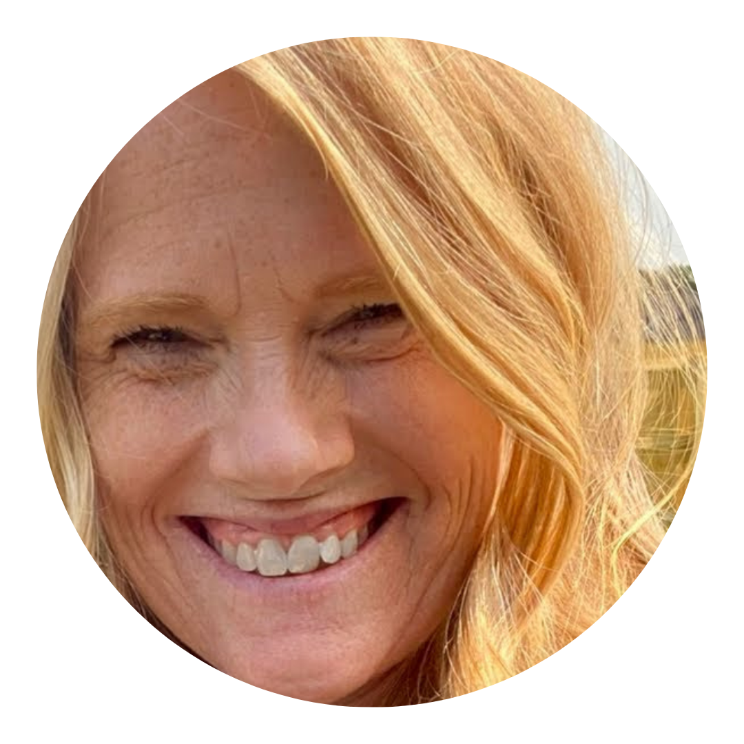Woman with blonde hair smiling widely outdoors.