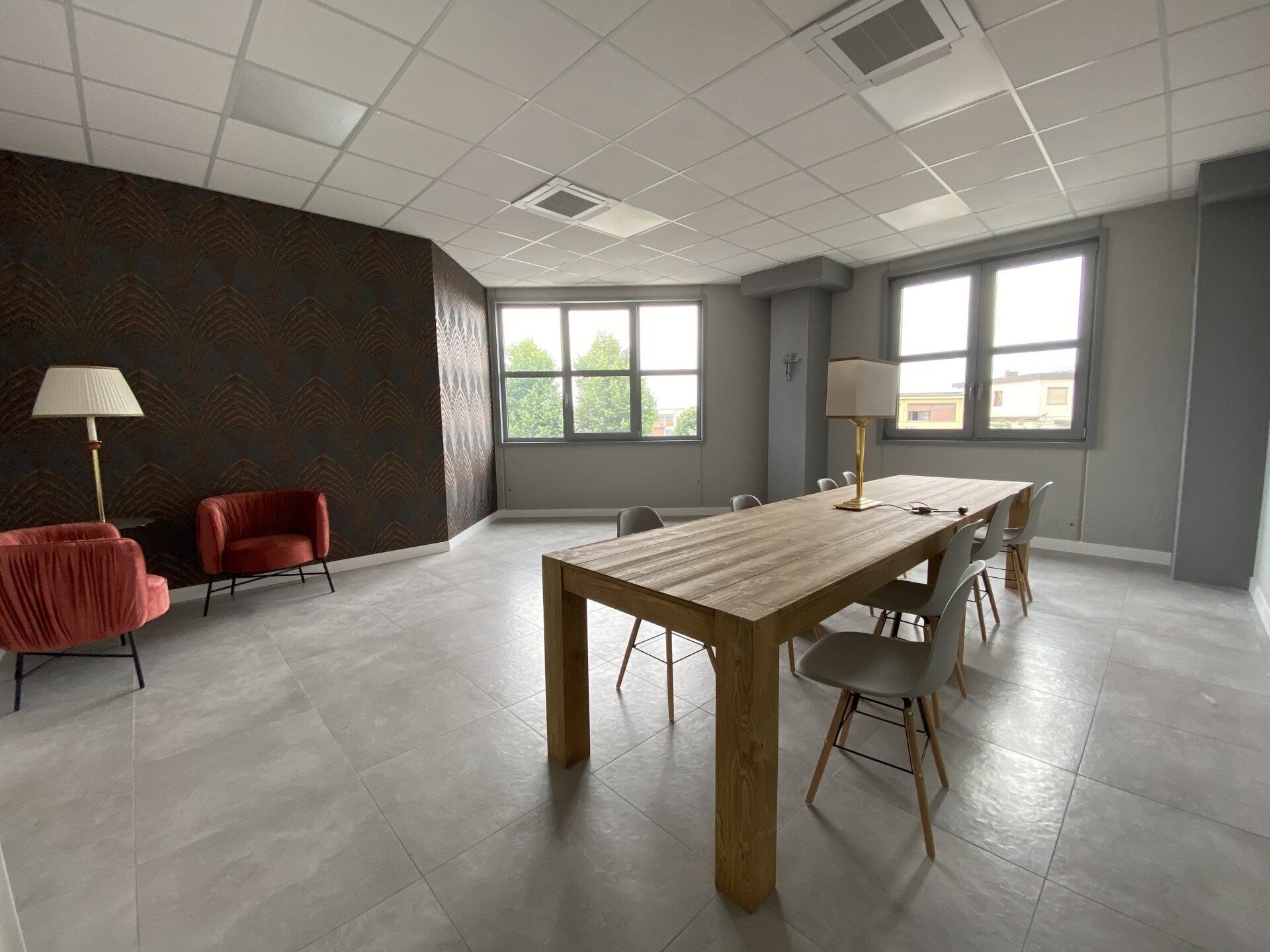sala riunioni con un grande tavolo di legno, sedie grigie, due poltrone rosse
