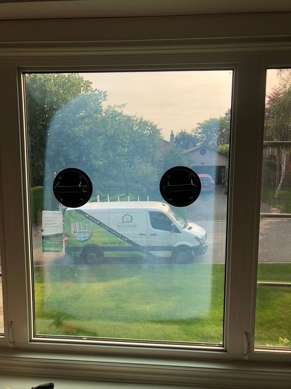 A white van is parked in front of a window.