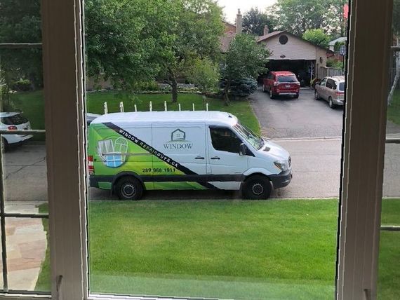 A green and white van is parked in front of a house