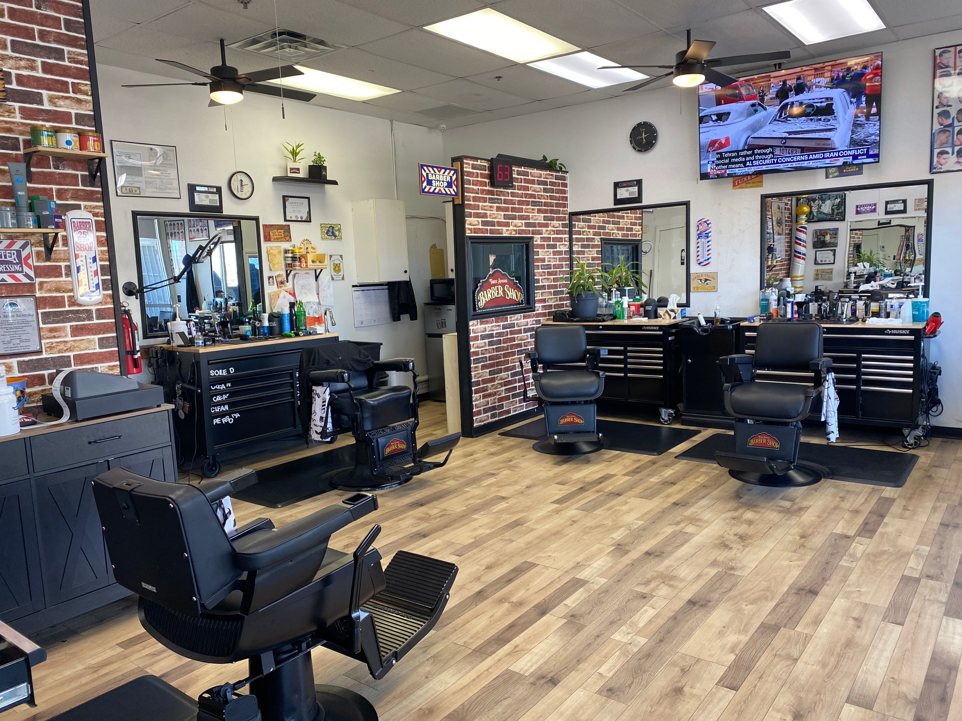 Man in a barber chair getting a haircut with others waiting in a shop.