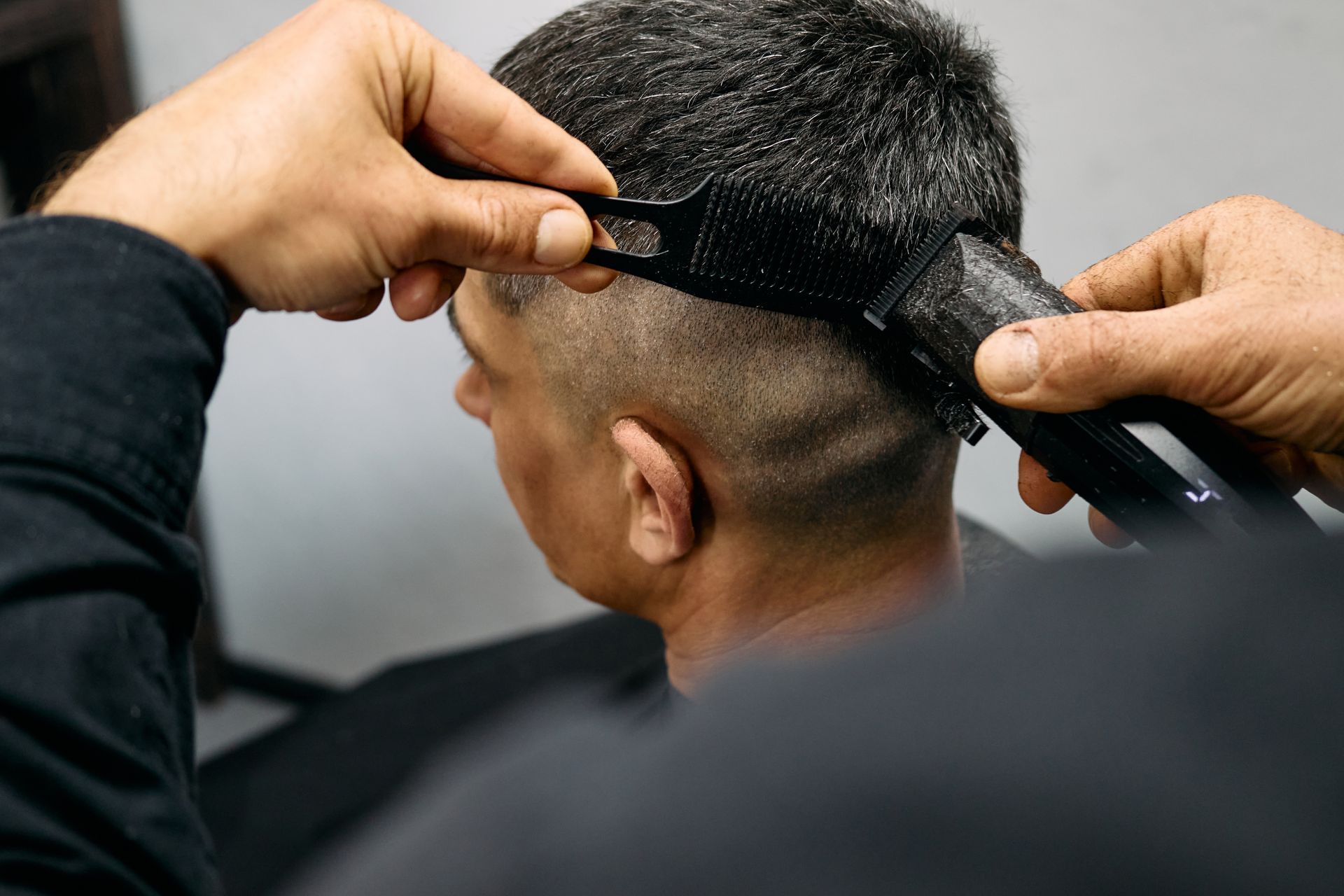 Barber cutting hair with clippers and comb.