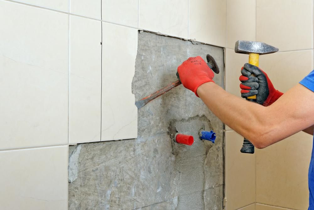 A Man Is Using a Hammer to Remove Tiles from A Wall — Nicho's Home Maintenance In Quirindi, NSW
