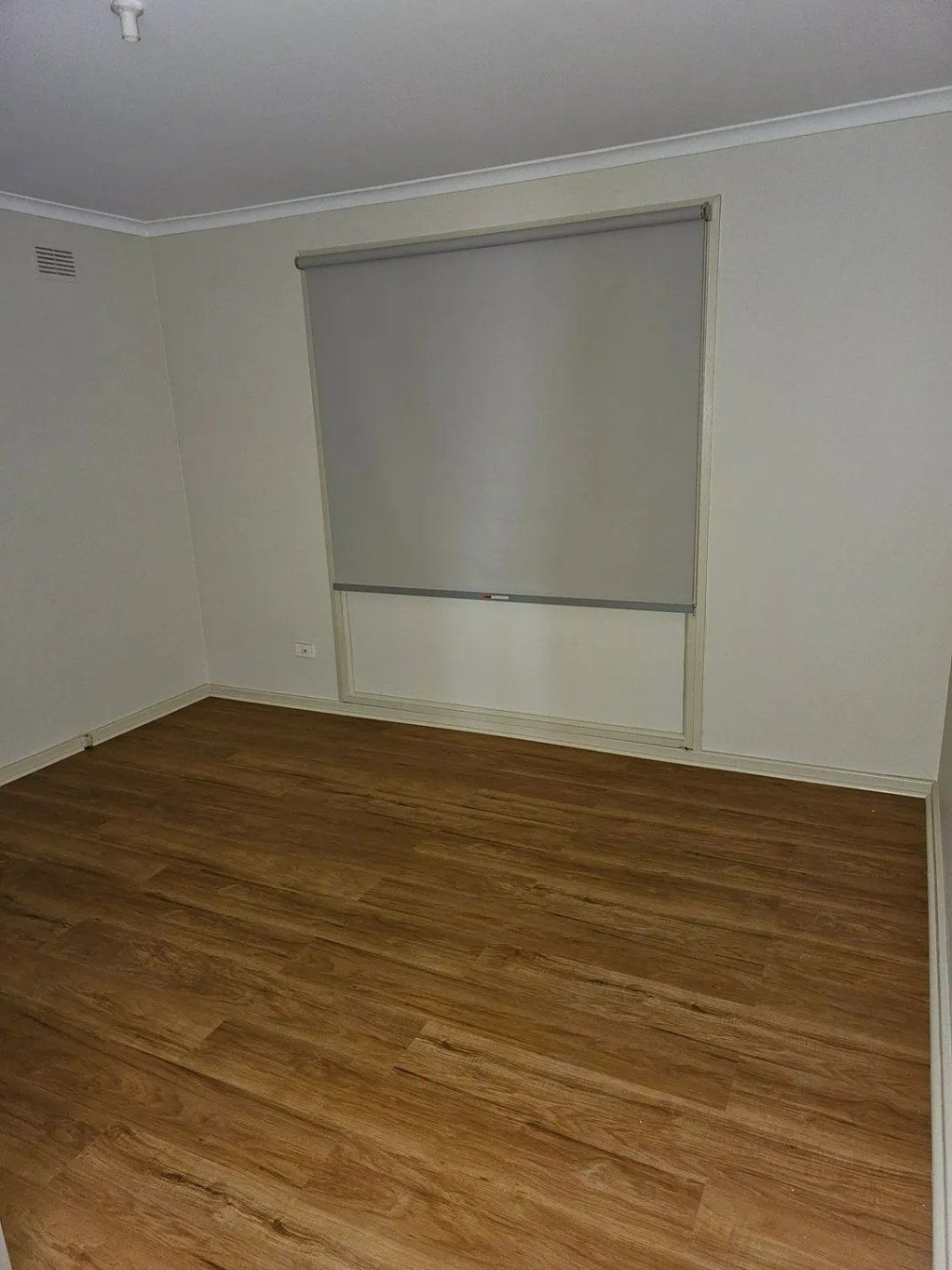 An Empty Room with Hardwood Floors and A Window with A Blind — Nicho's Home Maintenance In Narrabri, NSW