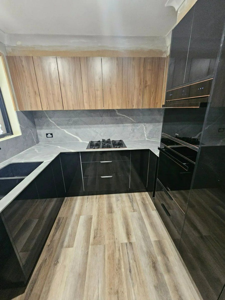 A Kitchen with Black Cabinets and Wooden Floors — Nicho's Home Maintenance In Narrabri, NSW