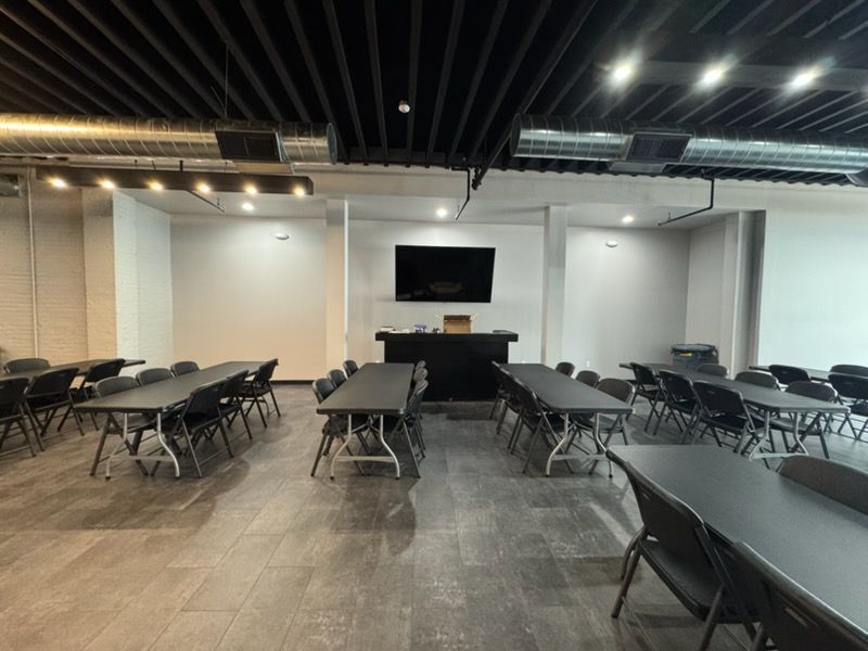 Empty conference room with tables and chairs facing a wall-mounted TV screen