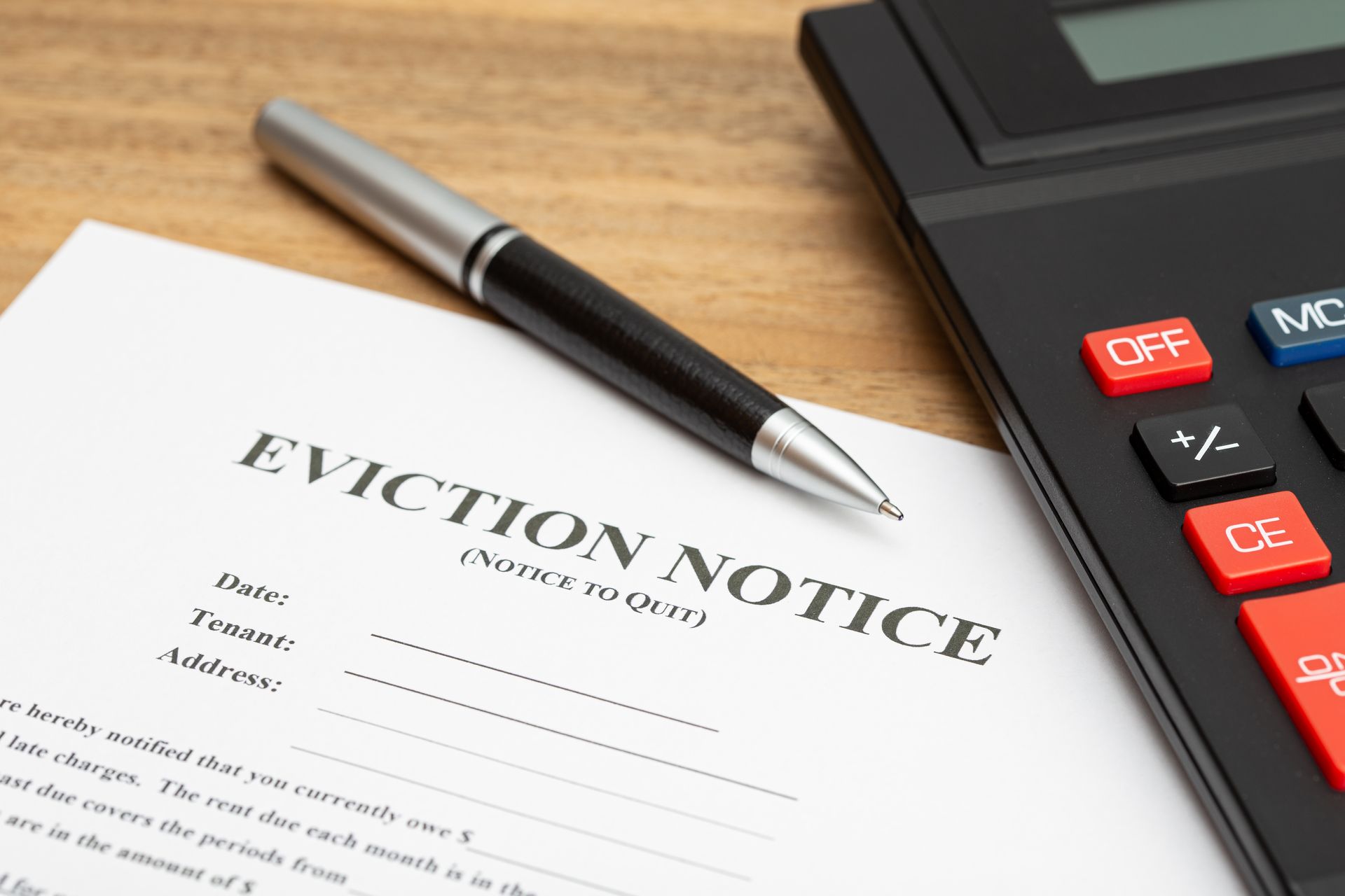Eviction notice with pen and calculator on wooden surface.