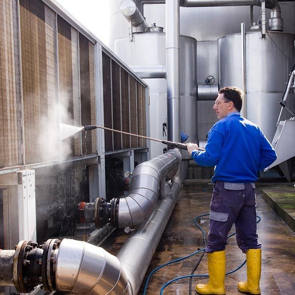 A man in a blue shirt and yellow boots is cleaning pipes A man in a blue shirt and yellow boots is cleaning pipes
