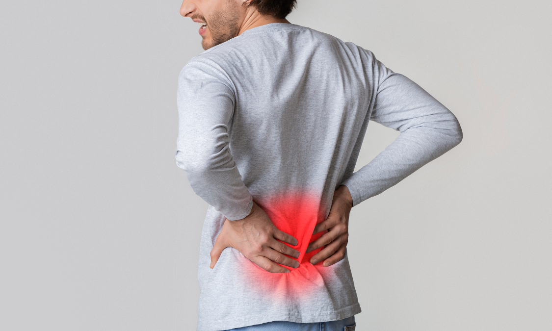 Man holding his lower back in pain, red highlight indicating the affected area.