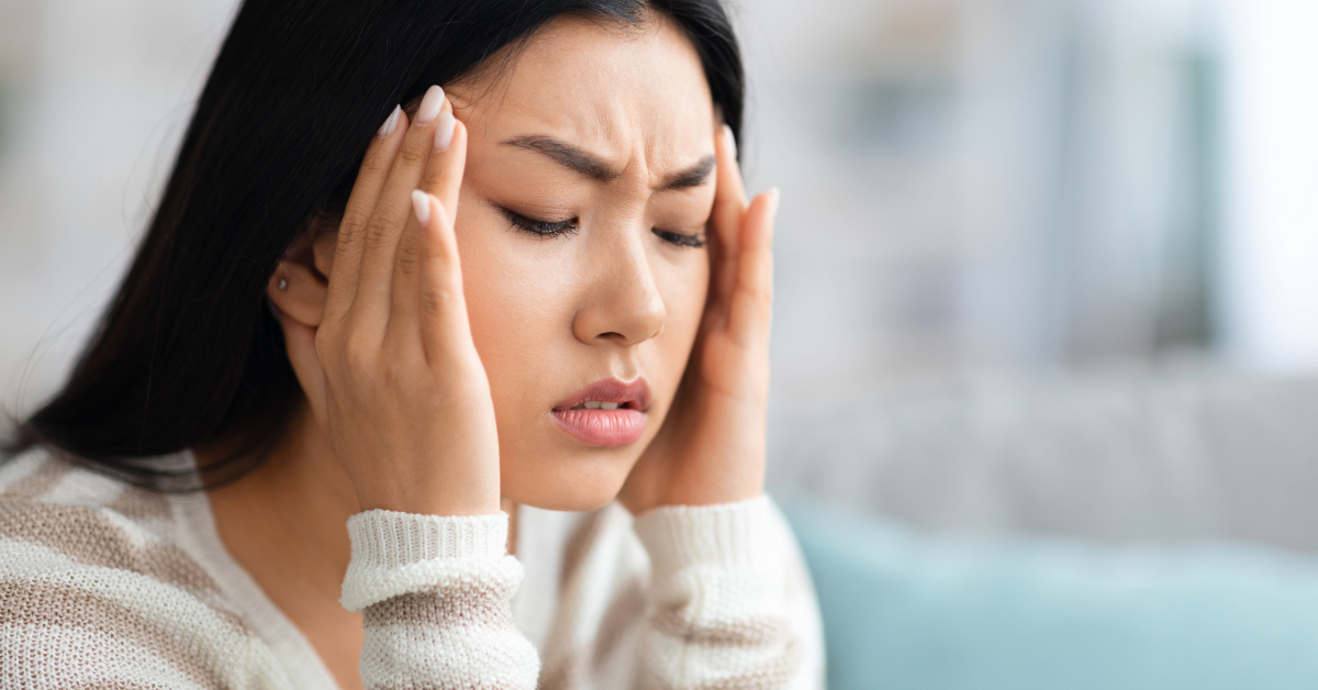 Woman holding her temples, eyes closed, appearing distressed.