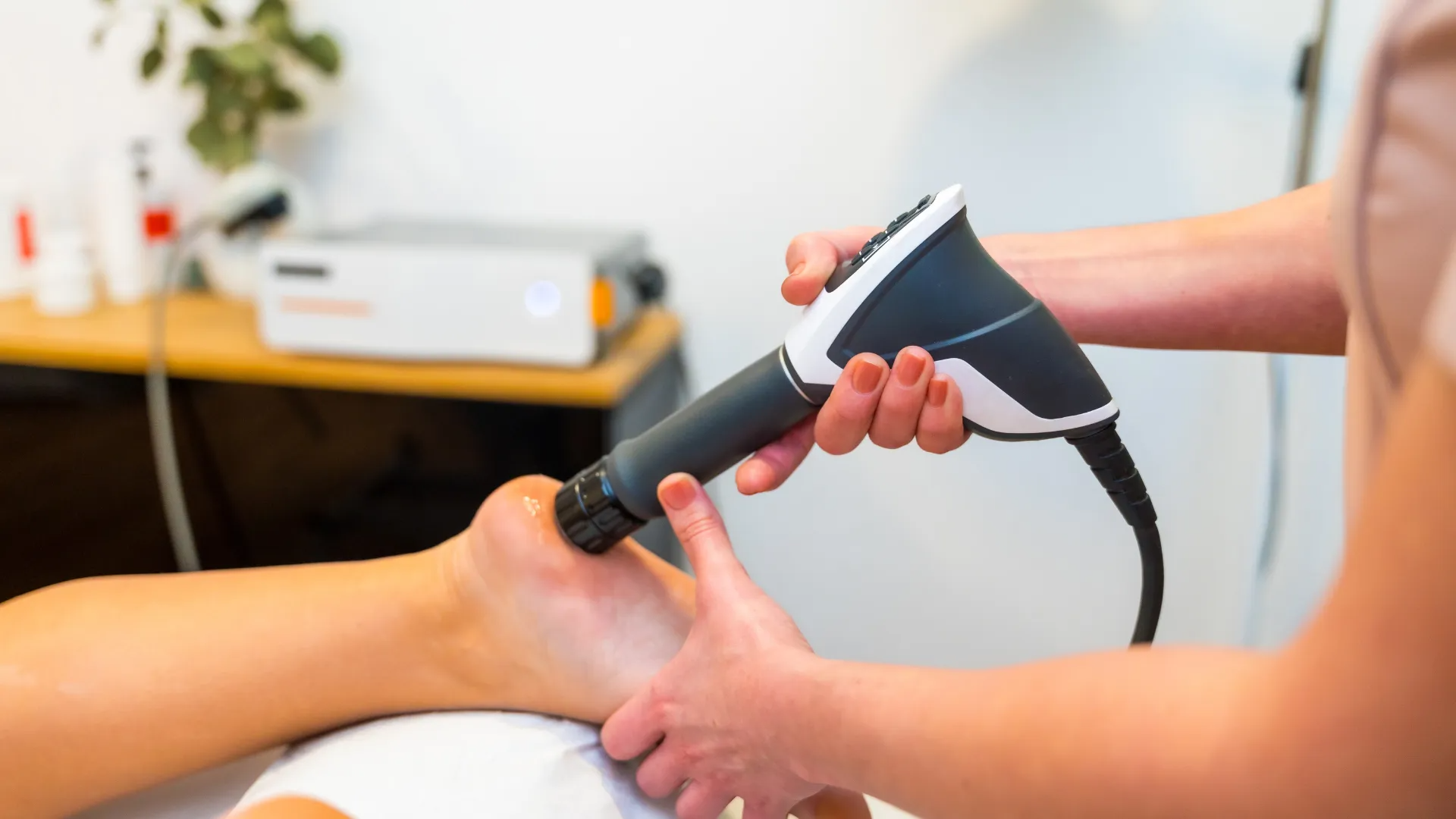 A person receiving medical treatment on their foot with a handheld device.