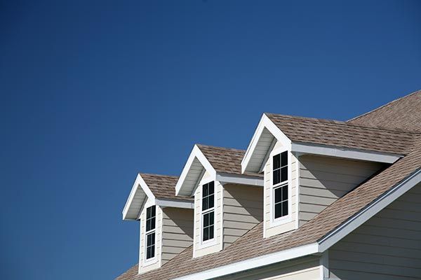 The roof of a house with three windows and a blue sky in the background. The roof of a house with three windows and a blue sky in the background.
