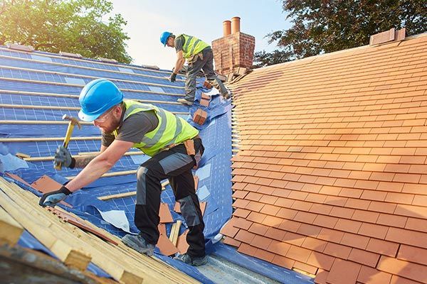 Two men are working on the roof of a house. Two men are working on the roof of a house.