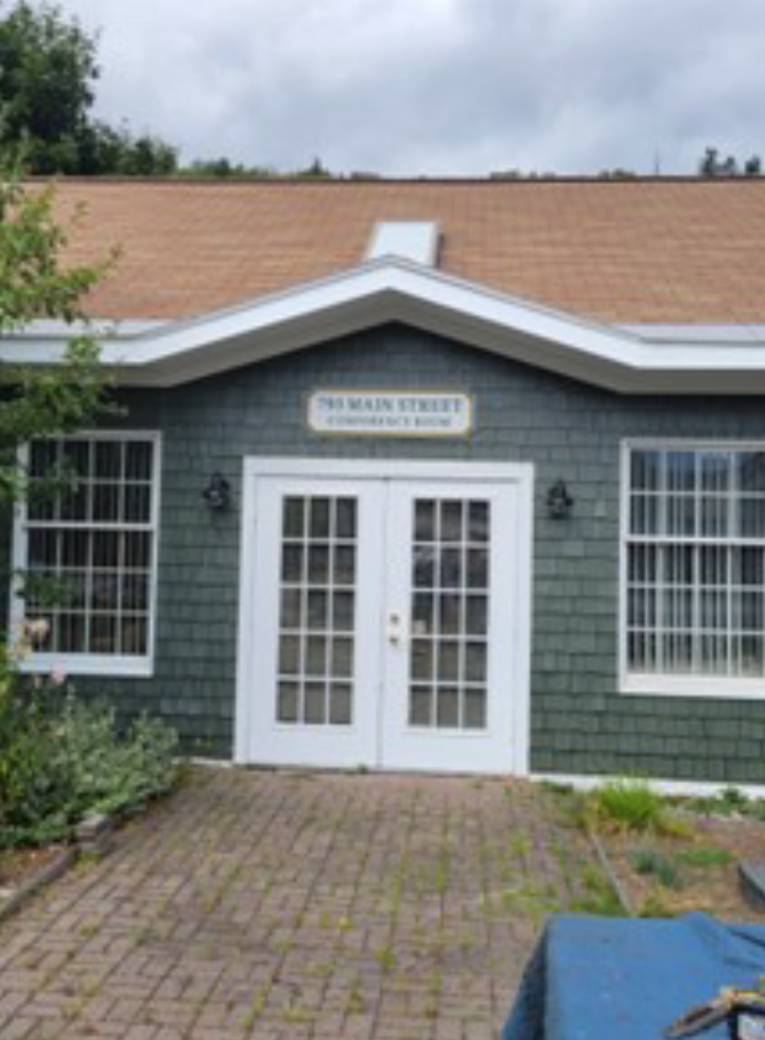 Green building with white doors, windows, and sign that reads 