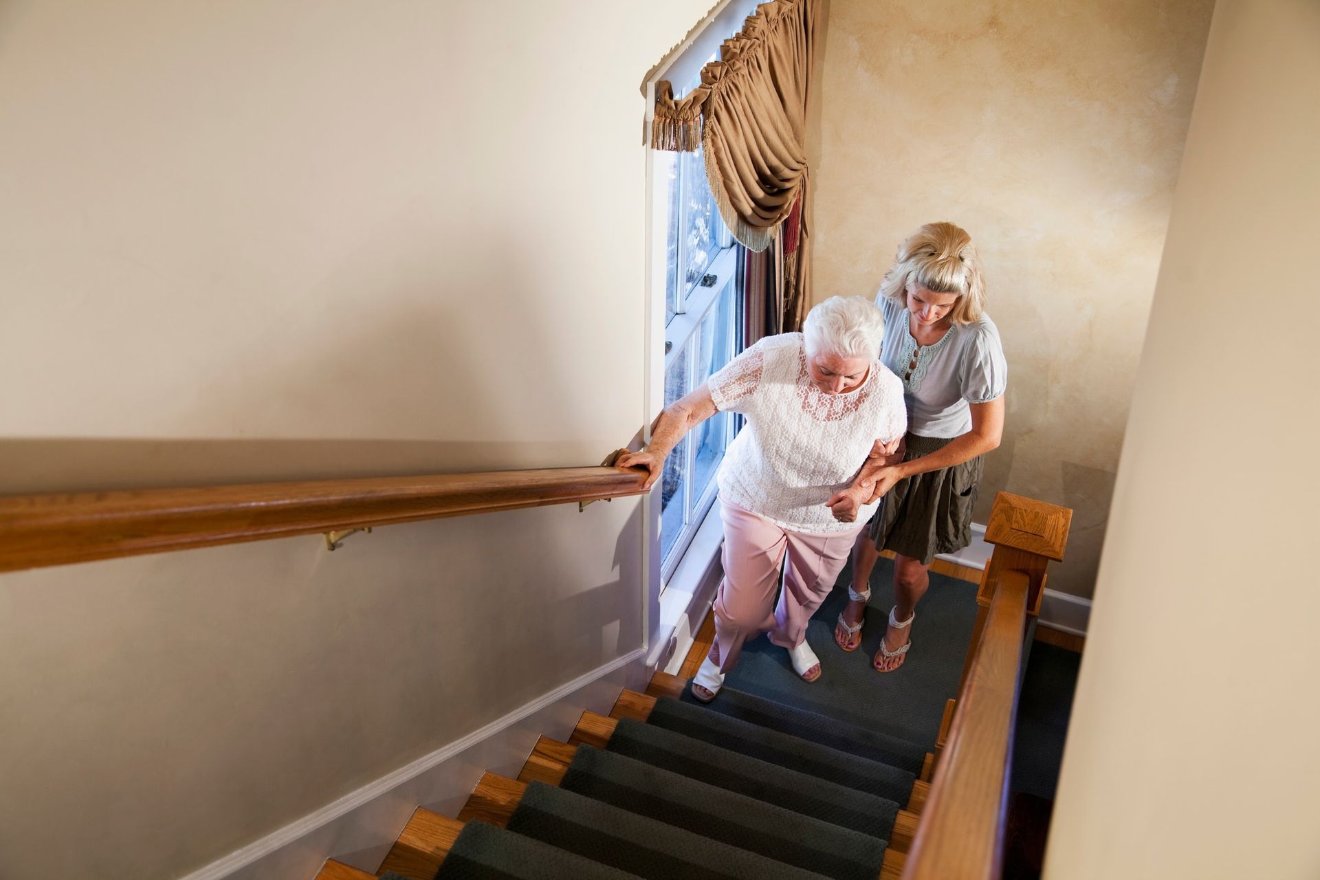 A woman is helping an older woman walk up the stairs.