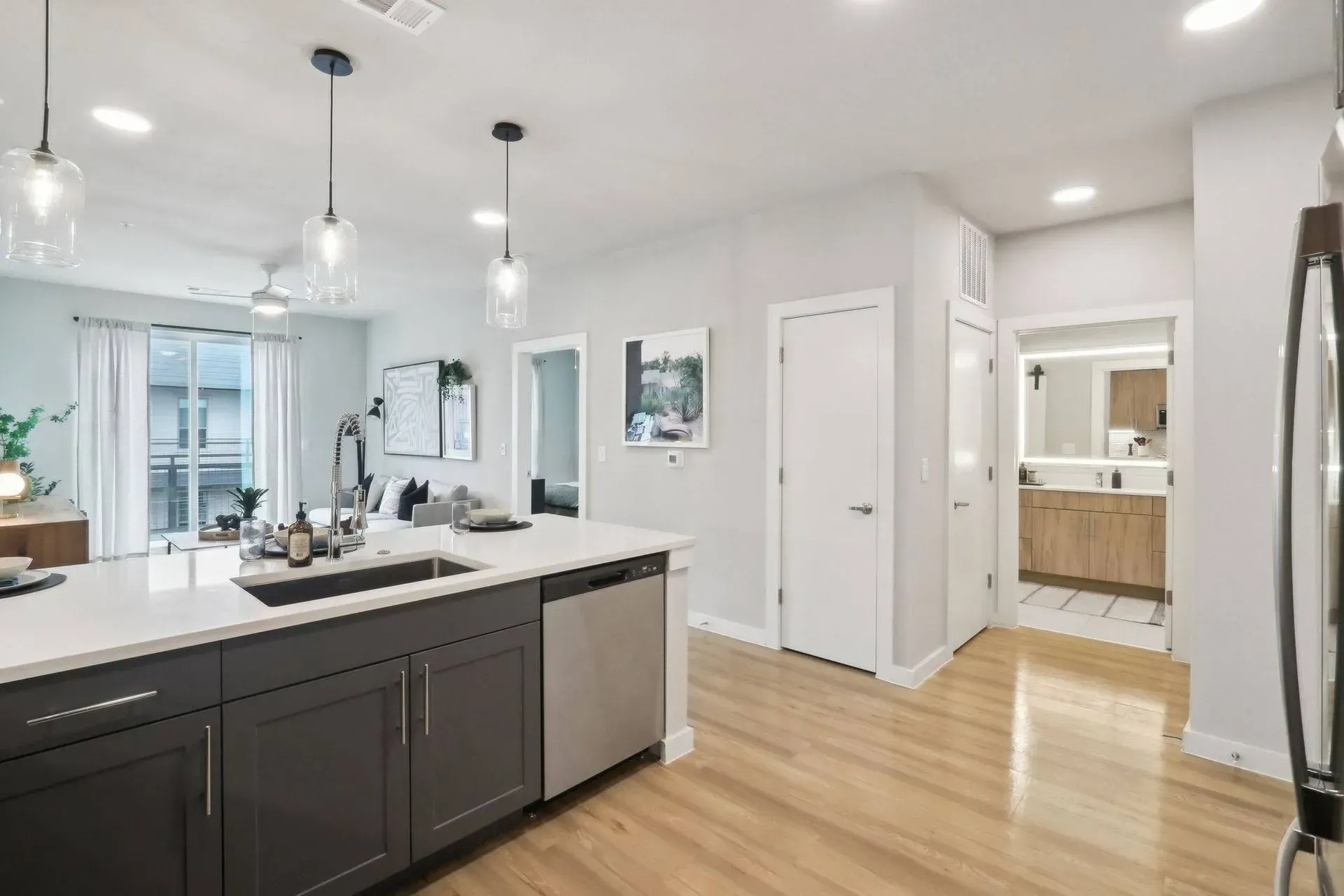 Modern kitchen with gray cabinets, white countertops, stainless steel appliances, and wood floors.