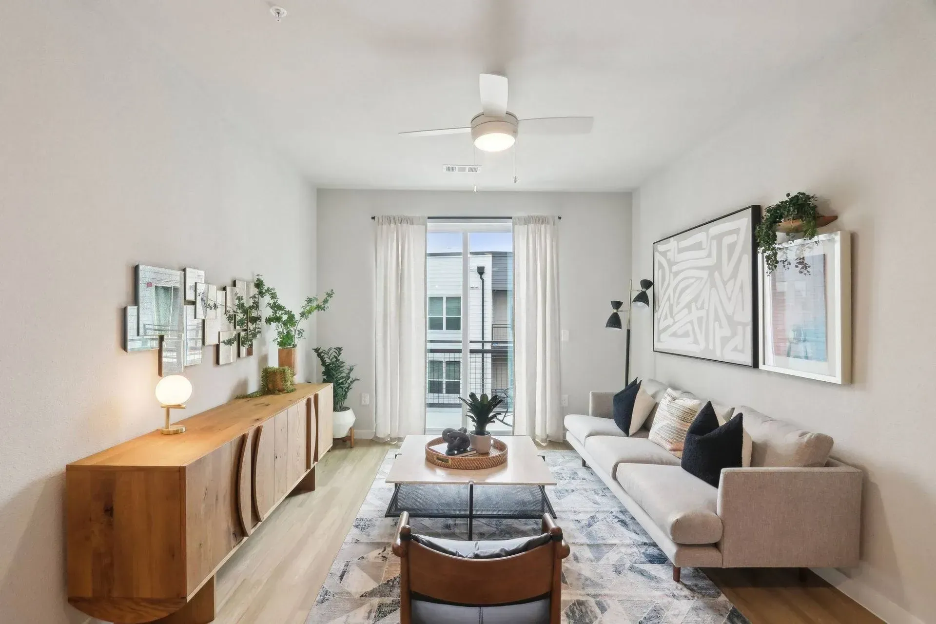 Living room with a white sofa, wooden cabinet, and abstract art.