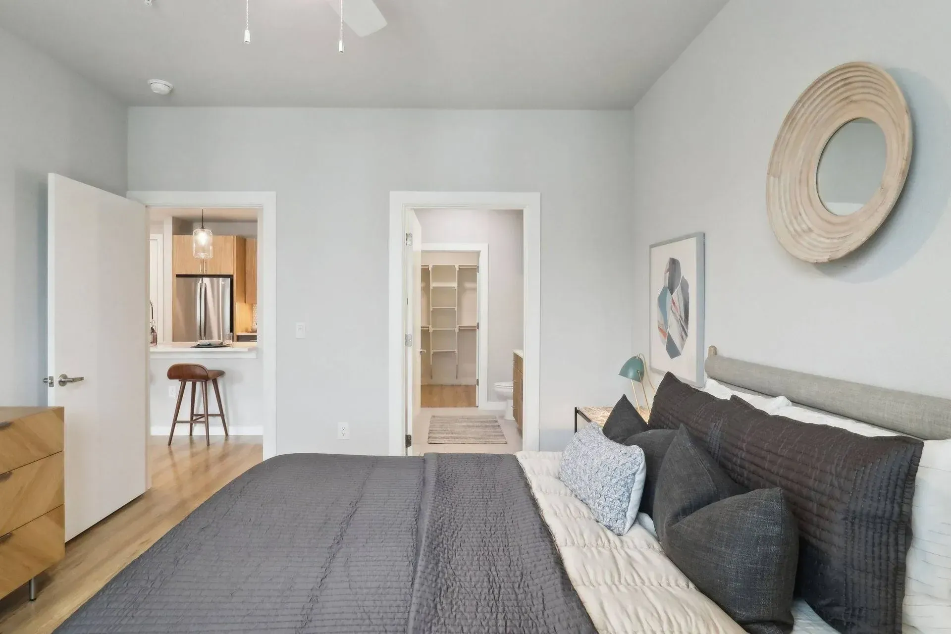 Bedroom with bed, doorway to kitchen, another doorway to walk-in closet. Light gray walls.