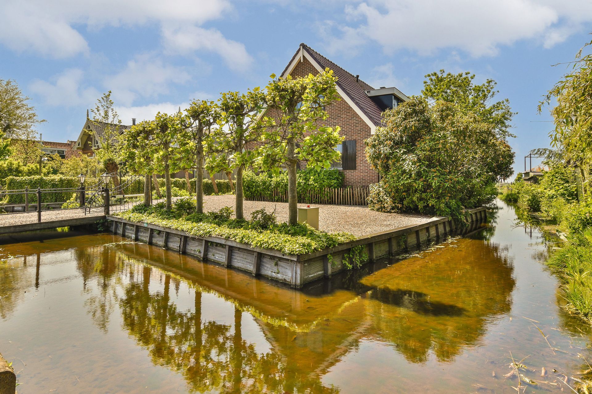 Een huis is omgeven door bomen naast een waterpartij.