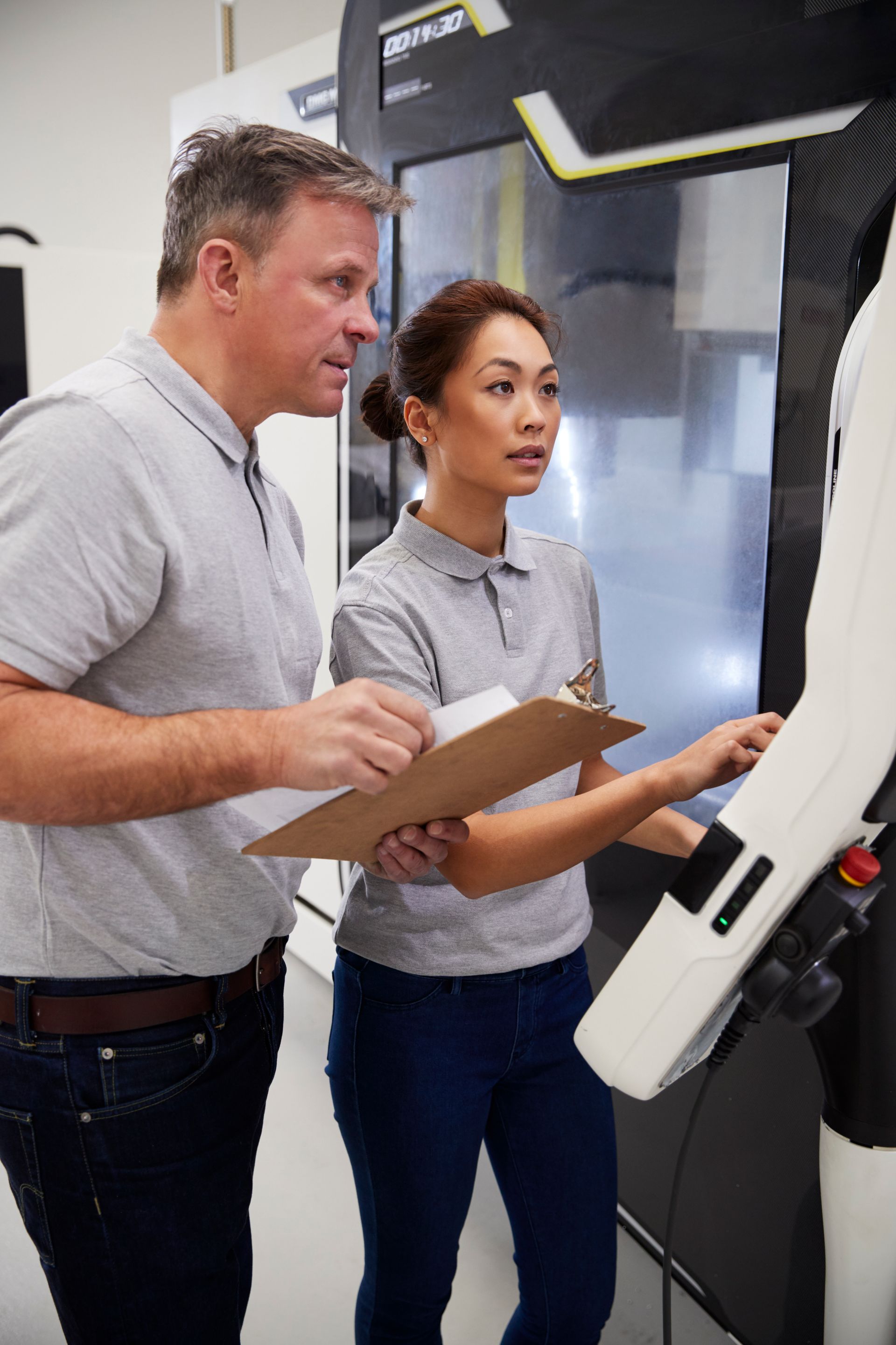 Een man en een vrouw kijken naar een machine in een fabriek.