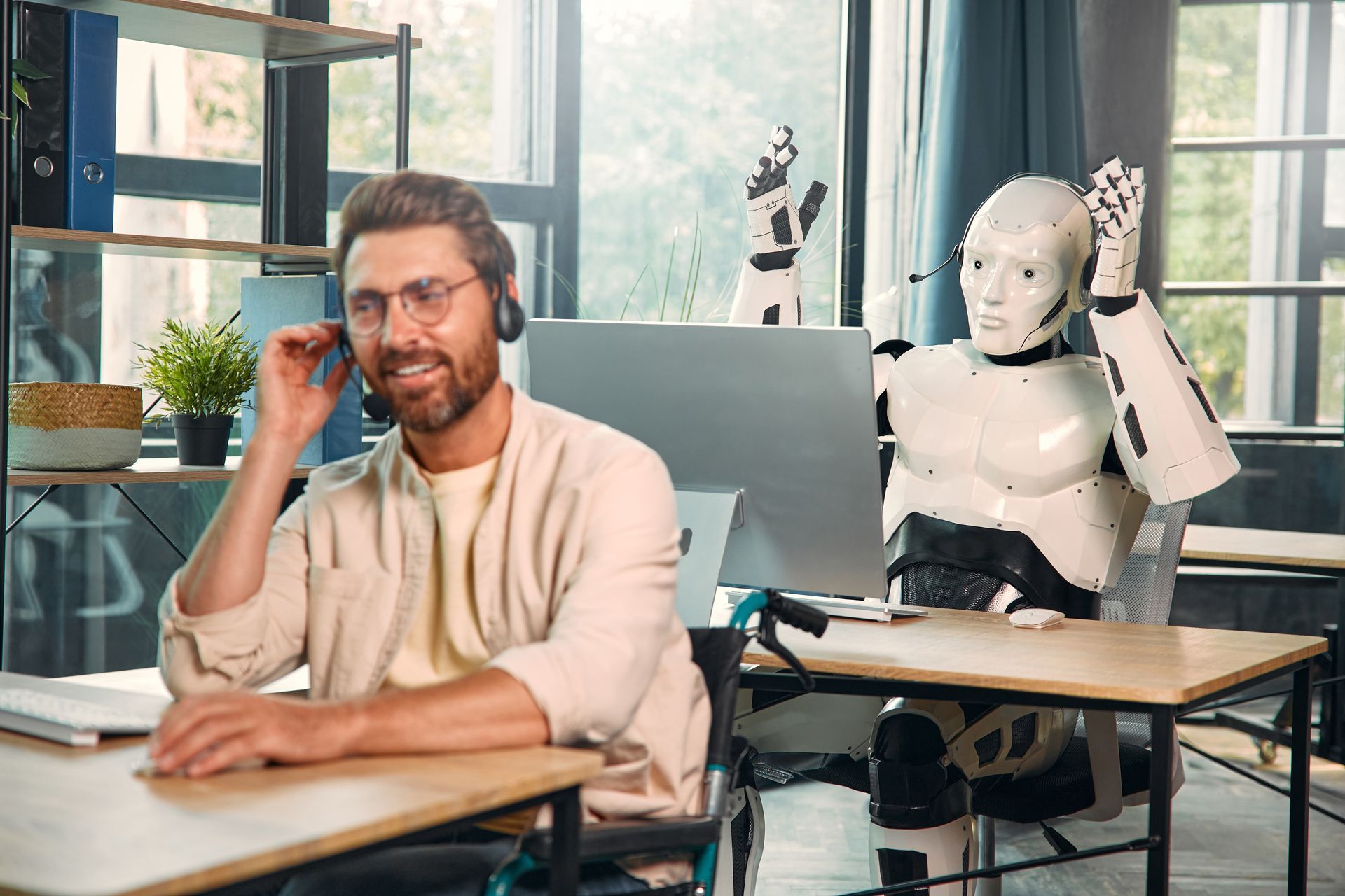 Een man zit aan een bureau en praat op een mobiele telefoon naast een robot.