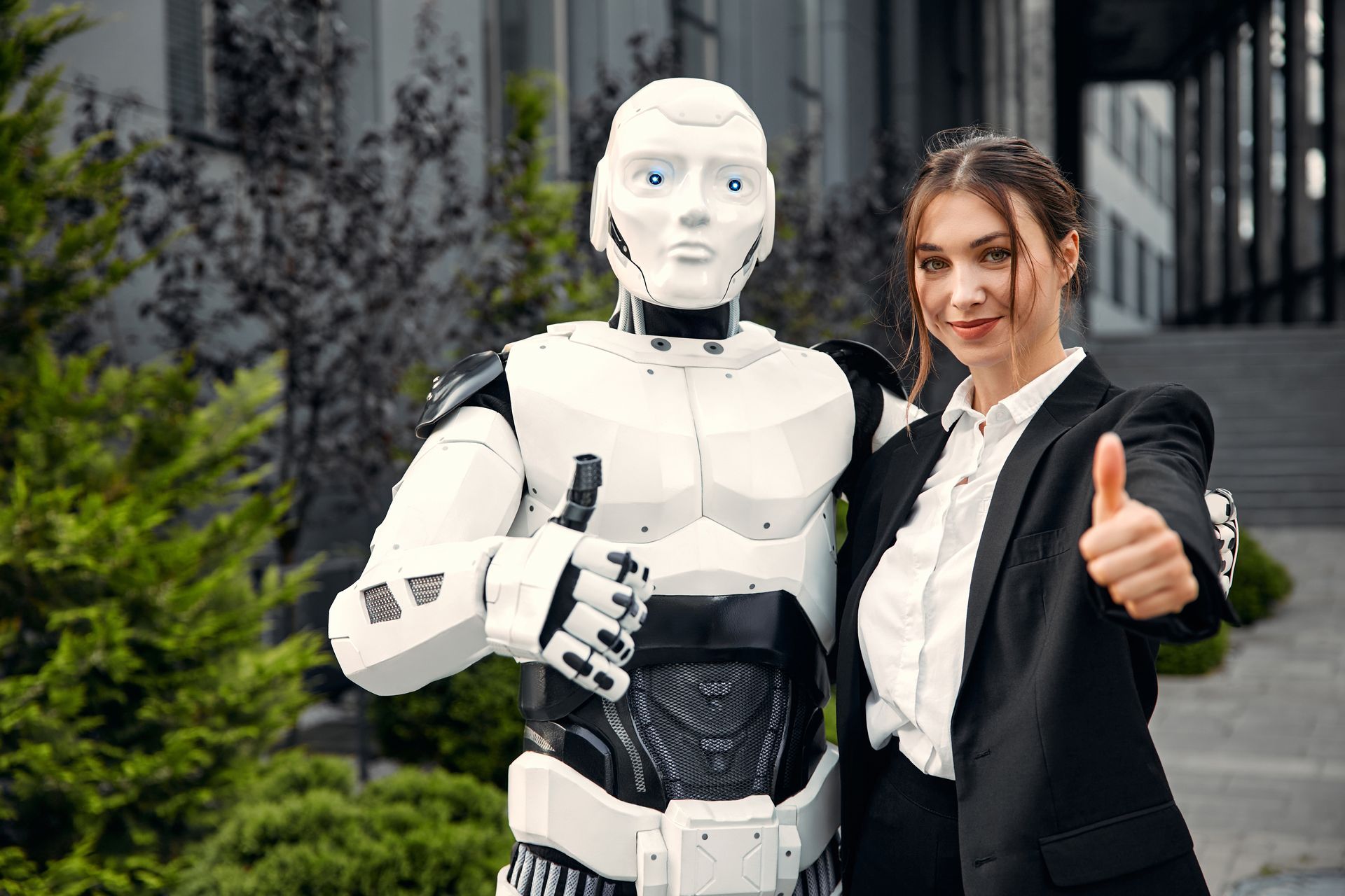 Een vrouw staat naast een robot en steekt haar duim omhoog.