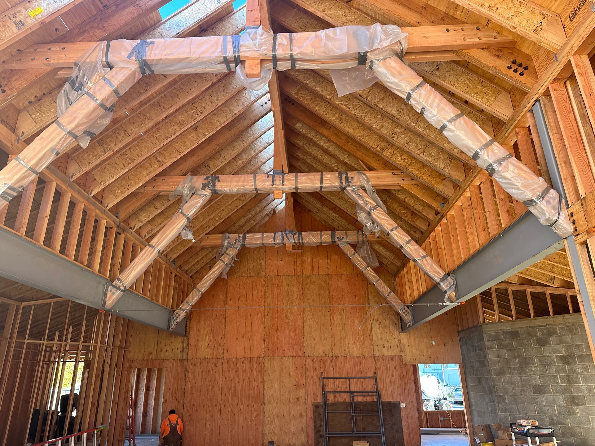 Interior framing of a house under construction, with exposed wooden rafters and beams.