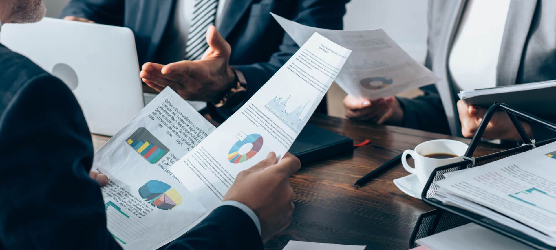 Picture of financial papers up close being held by hands of two businessmen
