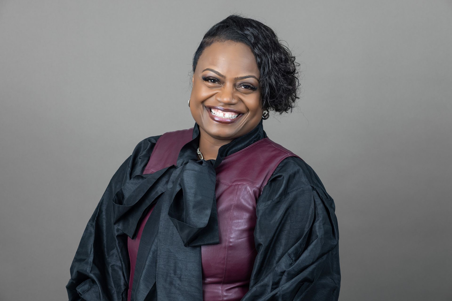 A woman in a black and burgundy outfit is smiling for the camera.