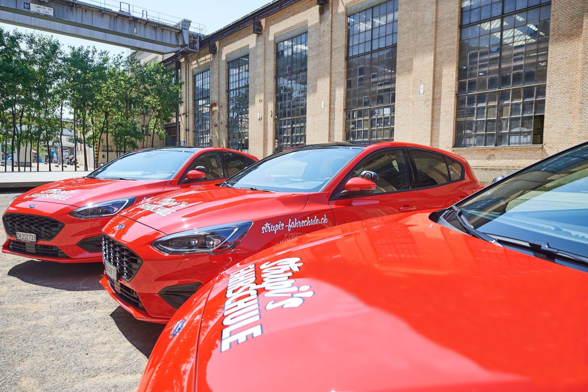 Rote Autos parkten vor einem Industriegebäude mit grossen Fenstern