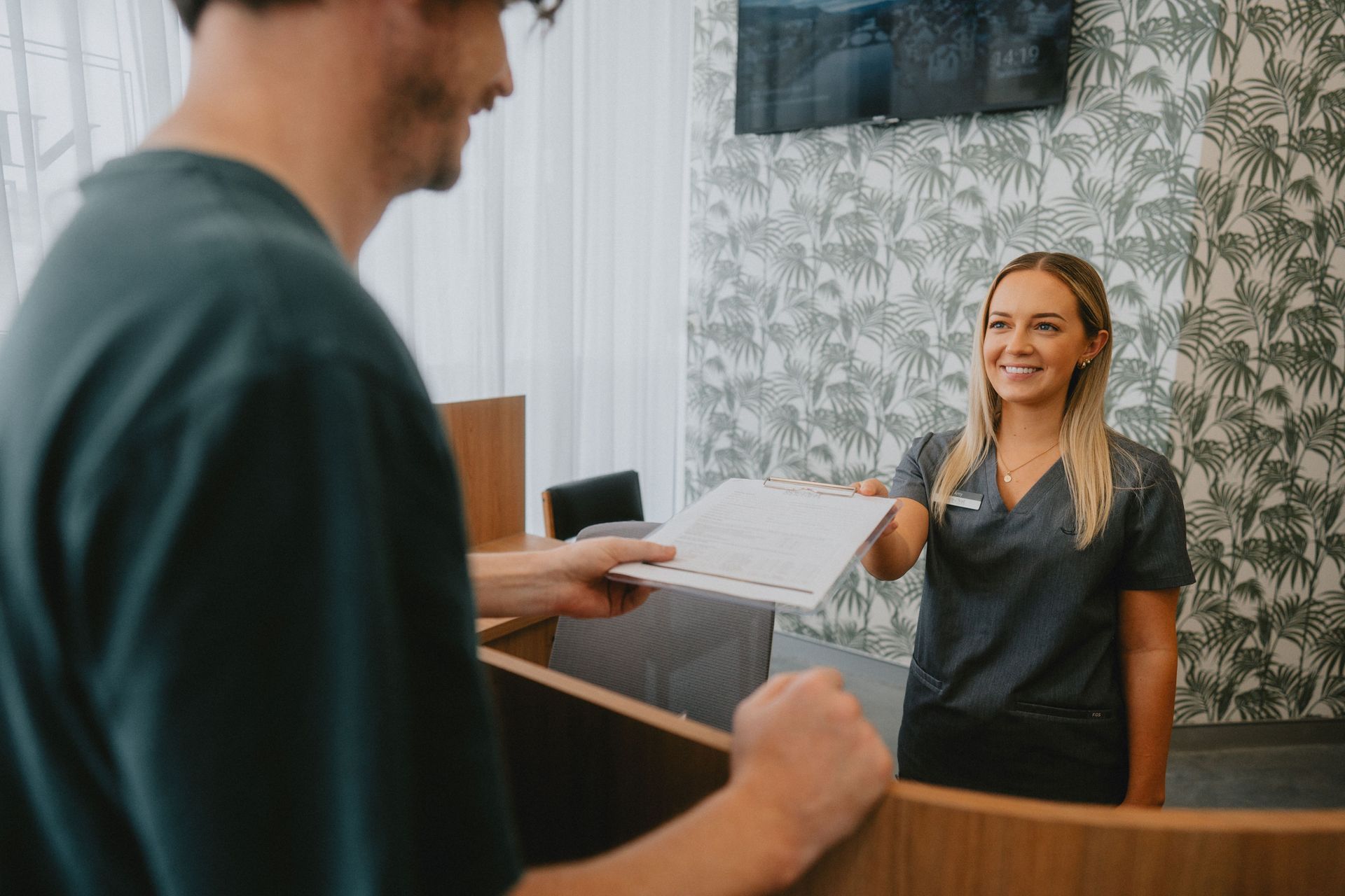 Receptionist Handing Paperwork to a Patient — New Leaf Dentists In Erina, NSW
