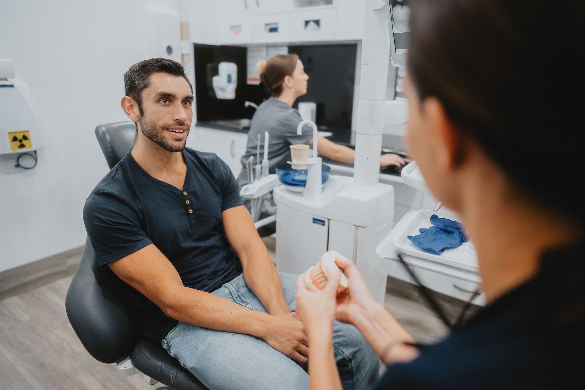 Man in a Dentist Chair, Looking at a Dentist Holding a Tool — New Leaf Dentists In Erina, NSW