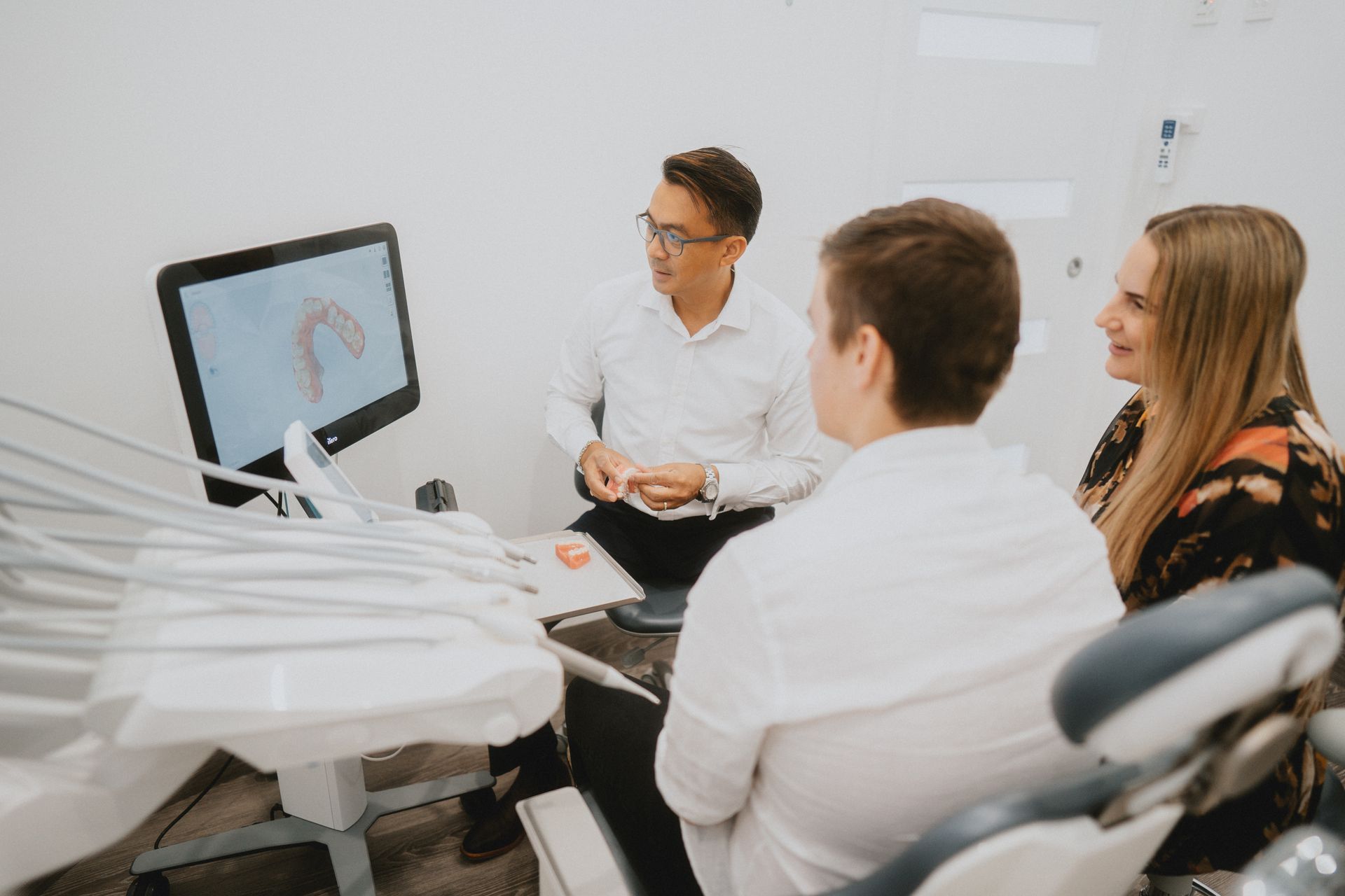 A Group of People Are Sitting in a Dental Chair Looking at a Computer Screen — New Leaf Dentists in Erina, NSW